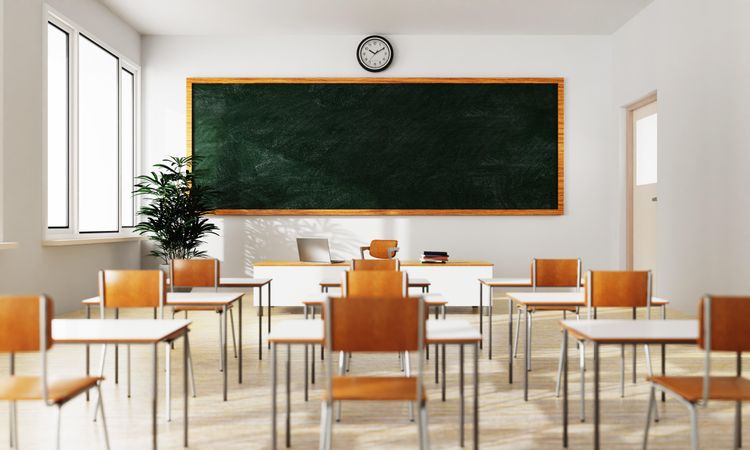 View of an empty chairs in classroom looking towards the teacher’s desk