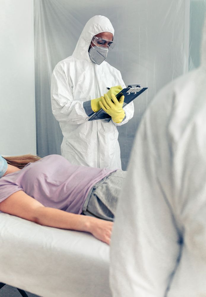 Doctors in bacteriological protection doing medical check to patient lying on a gurney