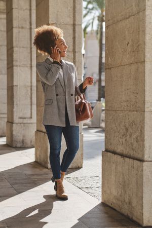 Cheerful Black female making phone call on summer street