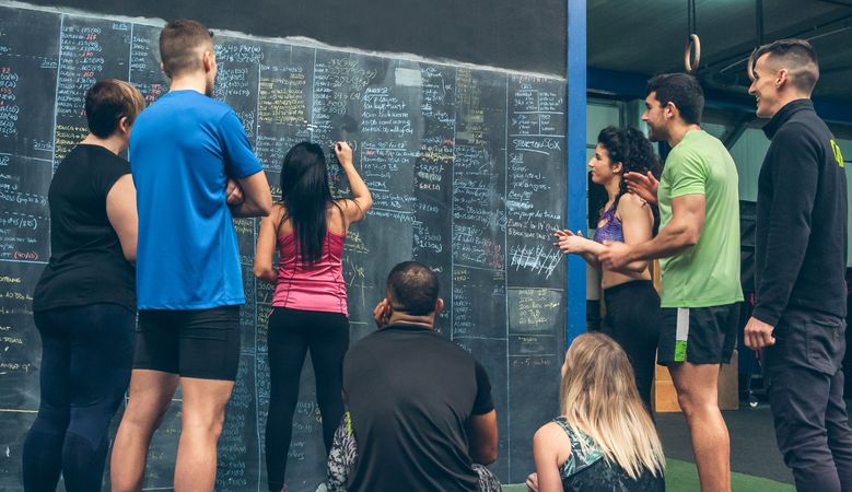 Athlete woman writing down results on the gym board