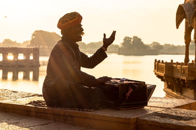 Sikh man sitting by the river at sunset