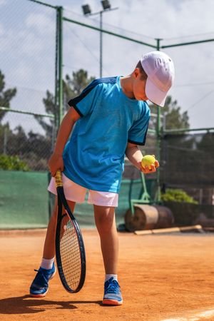Little boy playing tennis on a dirt court