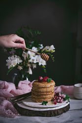 Pile of raspberry pancakes with honey on plate