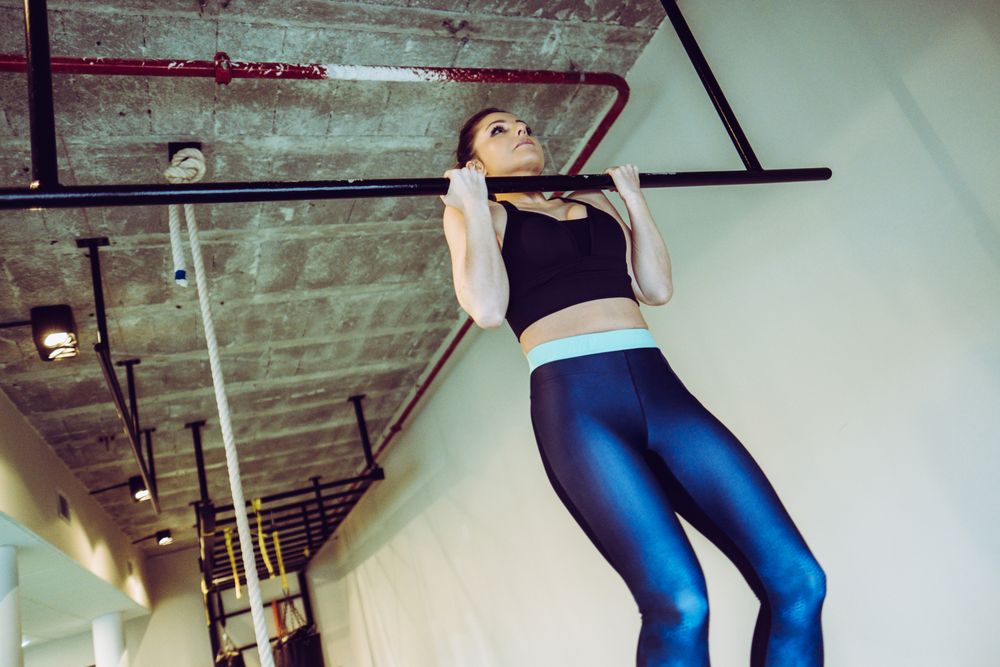 Young woman doing pull ups in gym