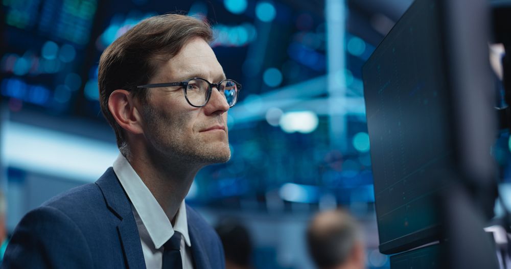 Professional Using Computer with Multiple Screens, Monitoring Financial Markets, Communicating with Corporate Business Partners