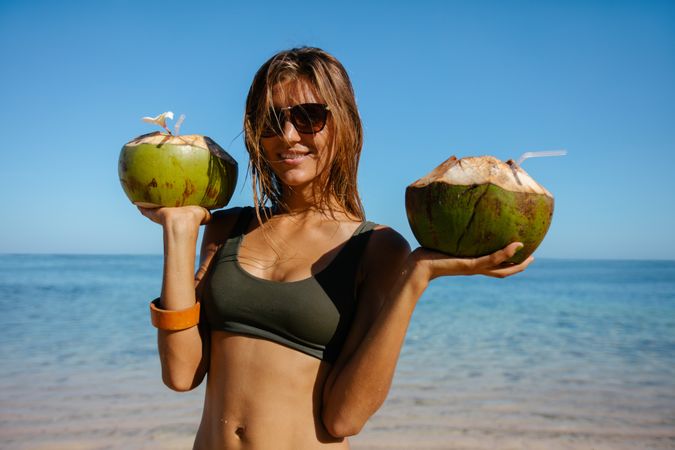 Beautiful woman on the beach with fresh coconuts
