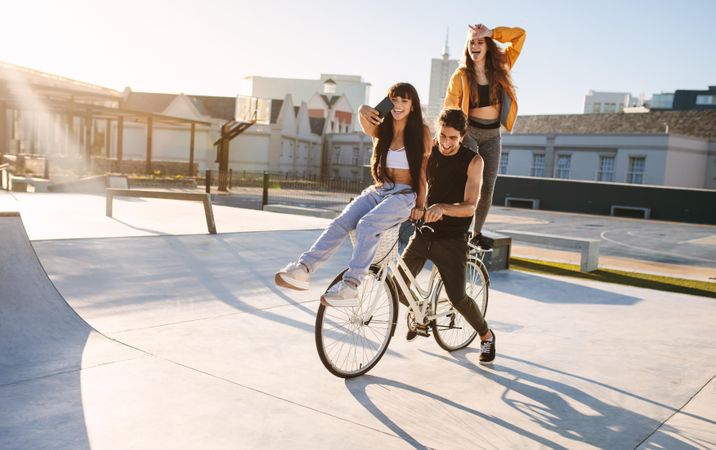 Young friends having fun taking selfie and riding bike outdoors