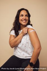 Female holding up her sleeve and showing her arm after getting a vaccine shot 4N9NZ5
