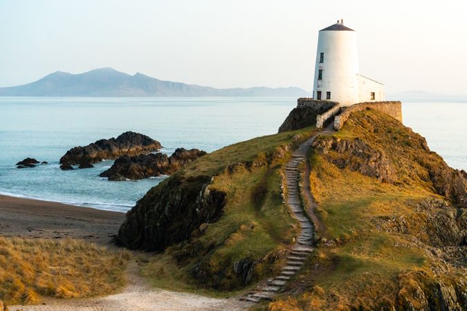 Lighthouse on hill on coastline at sunset