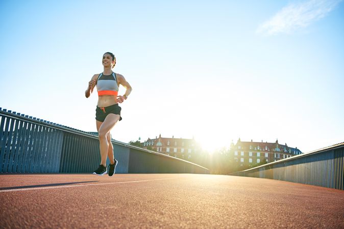 Happy woman jogging on bridge in the morning