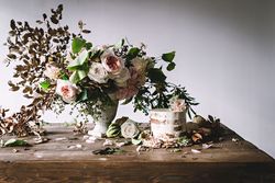 plate with cake decorated flower on table with bouquet of blooms in vase