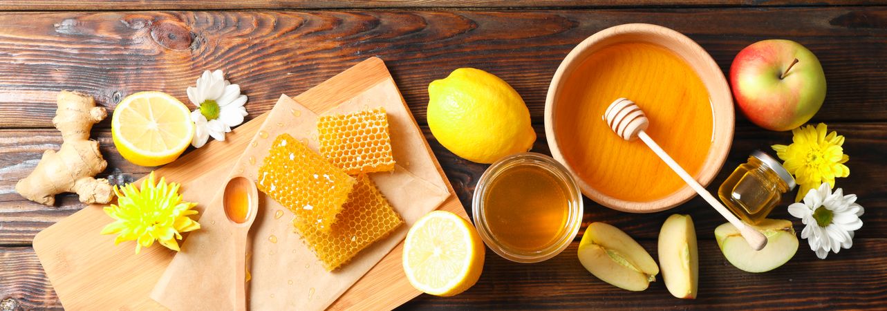Flat lay with honey, flowers and fruits on wood background