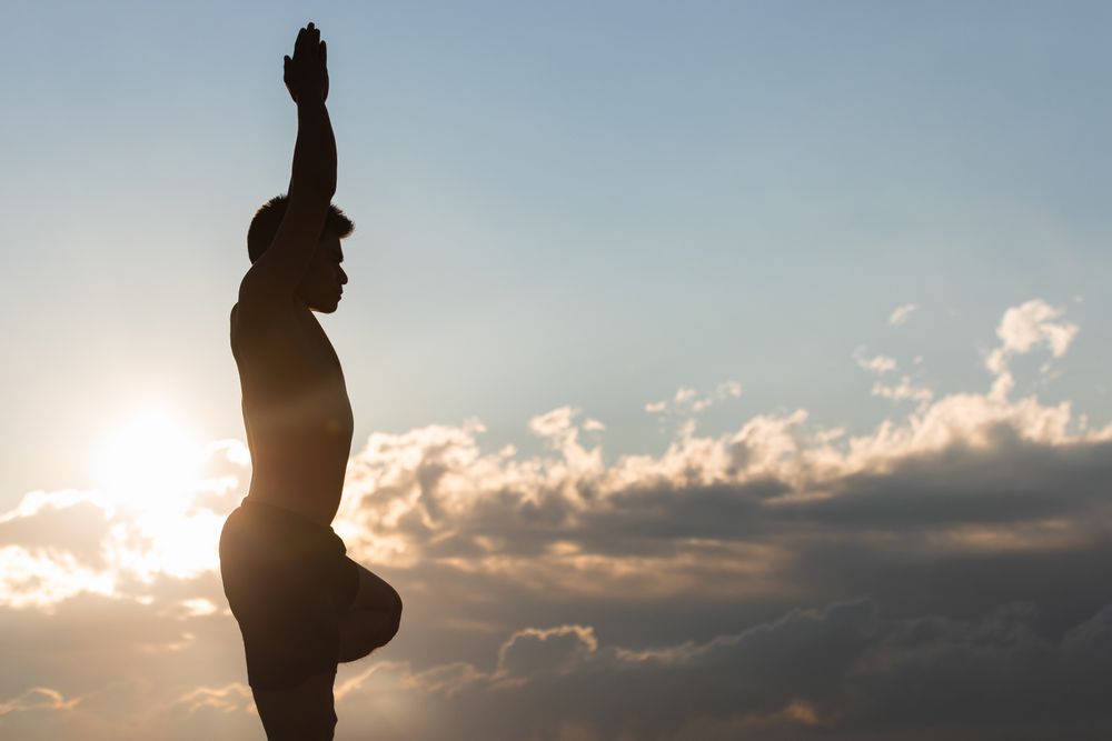 Man practicing yoga asana at sunset