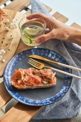 Anonymous person having breakfast with prosciutto toast and lime water on terrace