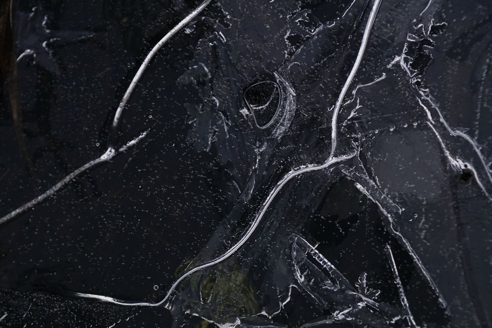 Fragment of thin ice on dark frozen river