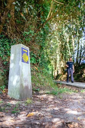Milestone of Saint James way with pilgrim walking