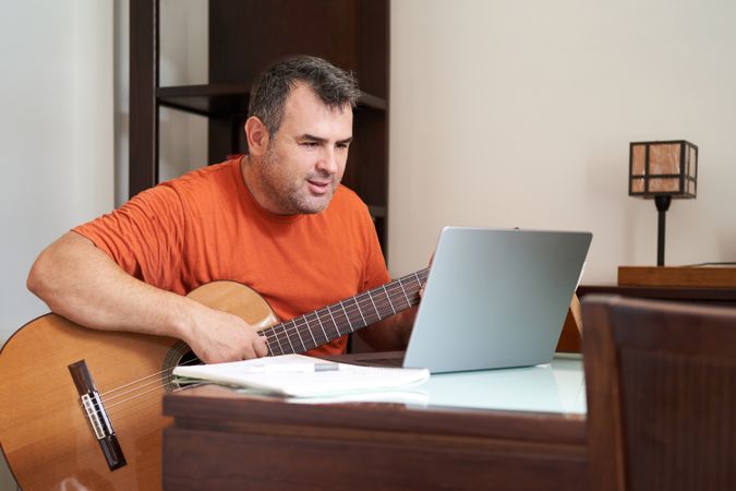 a man with laptop in online guitar lessons learning harmonics