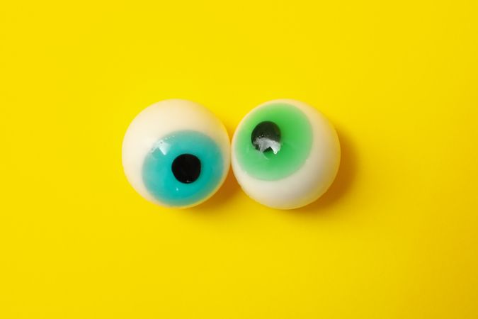 Candy eyes on yellow background, close up