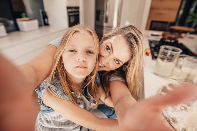 Parent and child posing for a selfie in kitchen