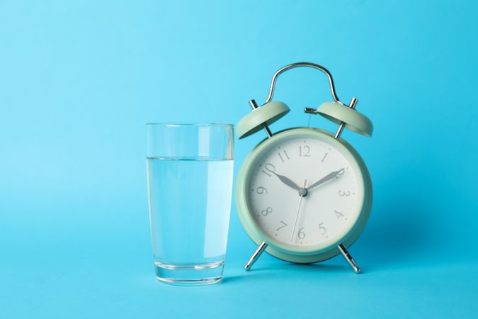 Glass of water next to alarm clock in blue room
