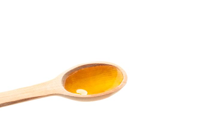 Wooden spoon with honey isolated on blank background, closeup