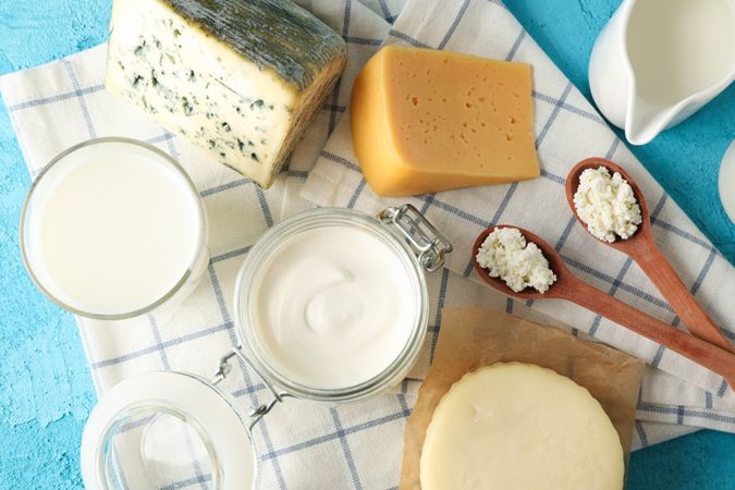 Fresh dairy products and kitchen towel on blue background