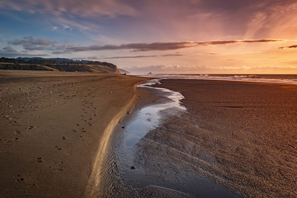 Tide going out on quiet beach at sunset