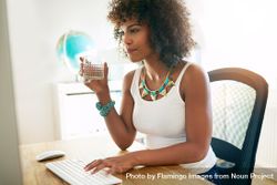 Black female sipping drink as she works at her computer 5RvRW5