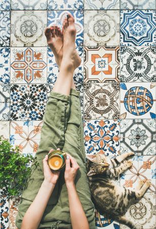 Woman on tiled terrace with coffee and cat