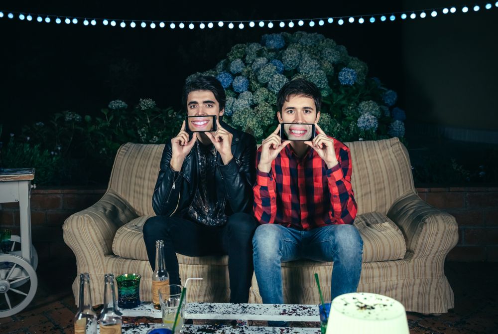 Funny men holding smartphones showing female mouths smiling