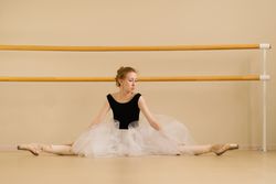 A ballet dancer performs a split in a dance studio