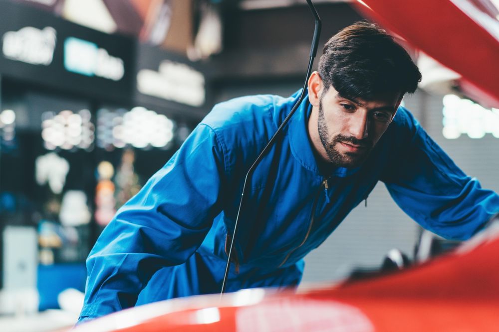 Male mechanic working on engine in vehicle