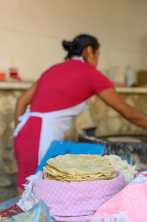 Woman making delicious corn tortillas