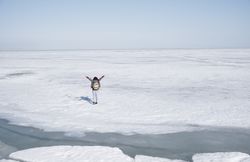 Young adult woman outdoors travelling with backpack in icy lands