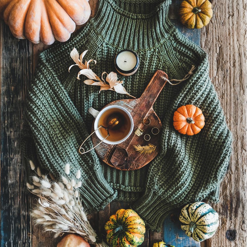 Flat-lay of dark green knitted sweater, and autumnal accessories, top view, square crop