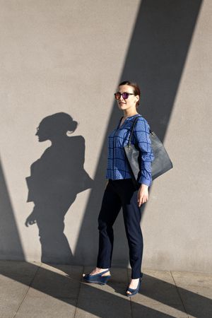 Smiling businesswoman standing near gray wall
