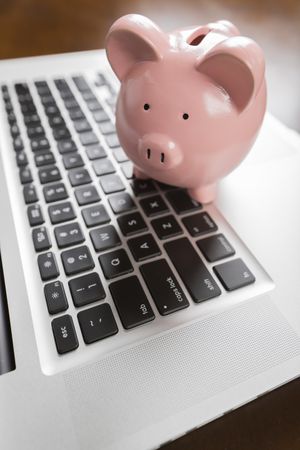 Piggy Bank Resting on Laptop Computer