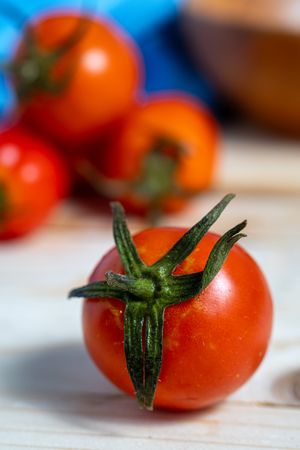 A bunch of red tomatoes are on a wooden table