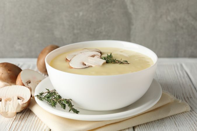 Bowl of creamy mushroom soup on napkin on wooden table