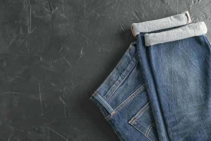 Folded jeans on dark background, space for text