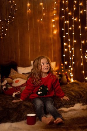 Little girl with mug surrounded by christmas decoration