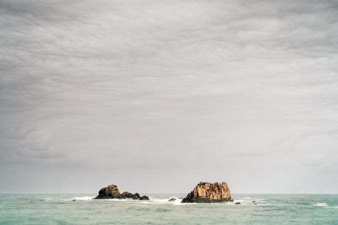 Rocky peaks protrude from water in cloudy day