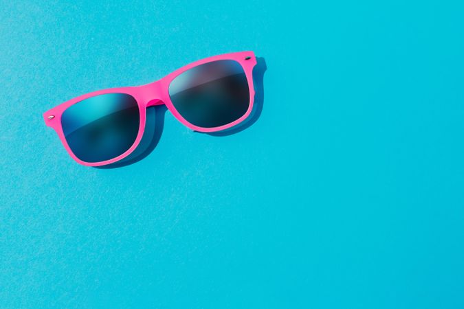 Pink sunglasses on blue background