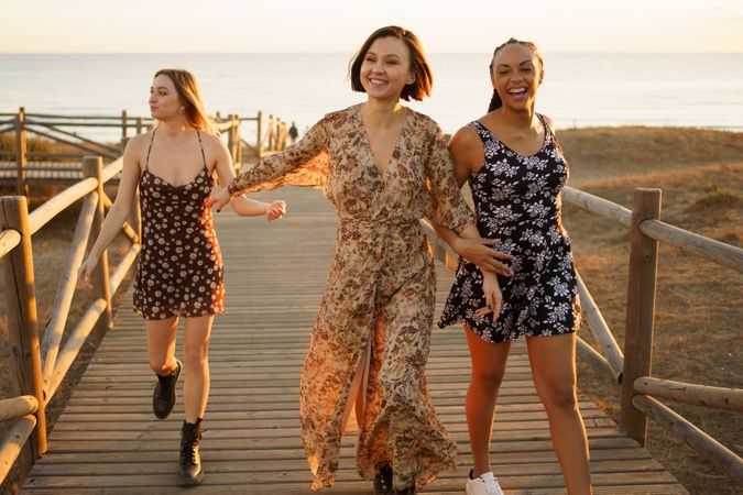 Three smiling woman walking on coastal pedestrian walkway