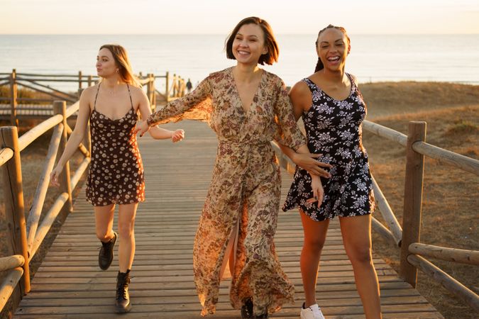 Three smiling woman walking on coastal pedestrian walkway