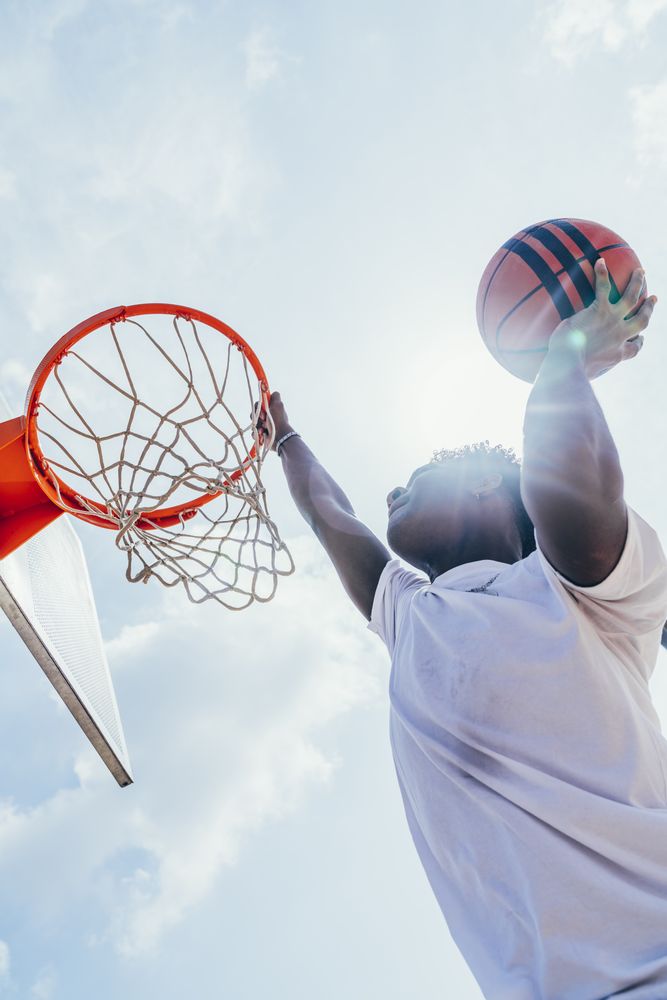 Black sportsman hanging on basketball lap