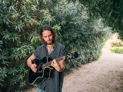 Hipster man in jungle with guitar