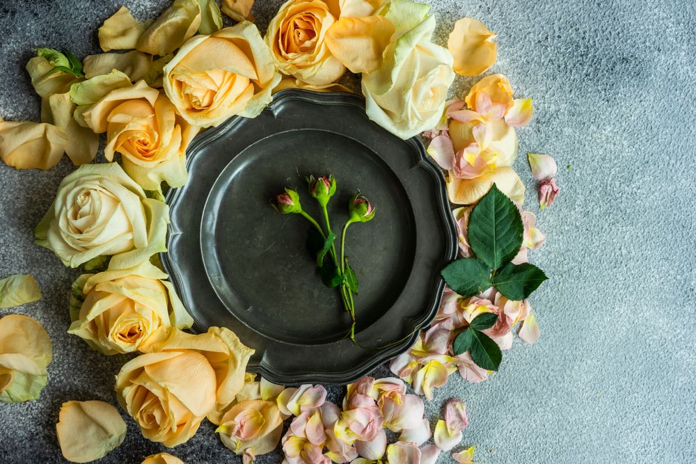 Beautiful floral card concept with fresh rose petals surrounding plate on counter