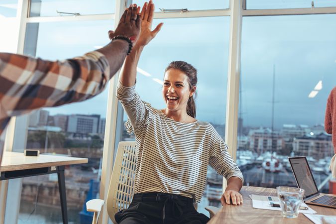 Business colleagues giving high five to each other in office