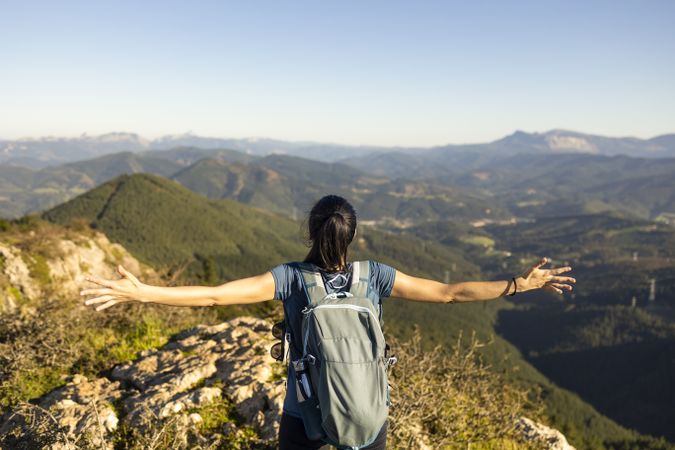 A woman opens her arms, marveling at the natural mountain scenery in the Basque Country